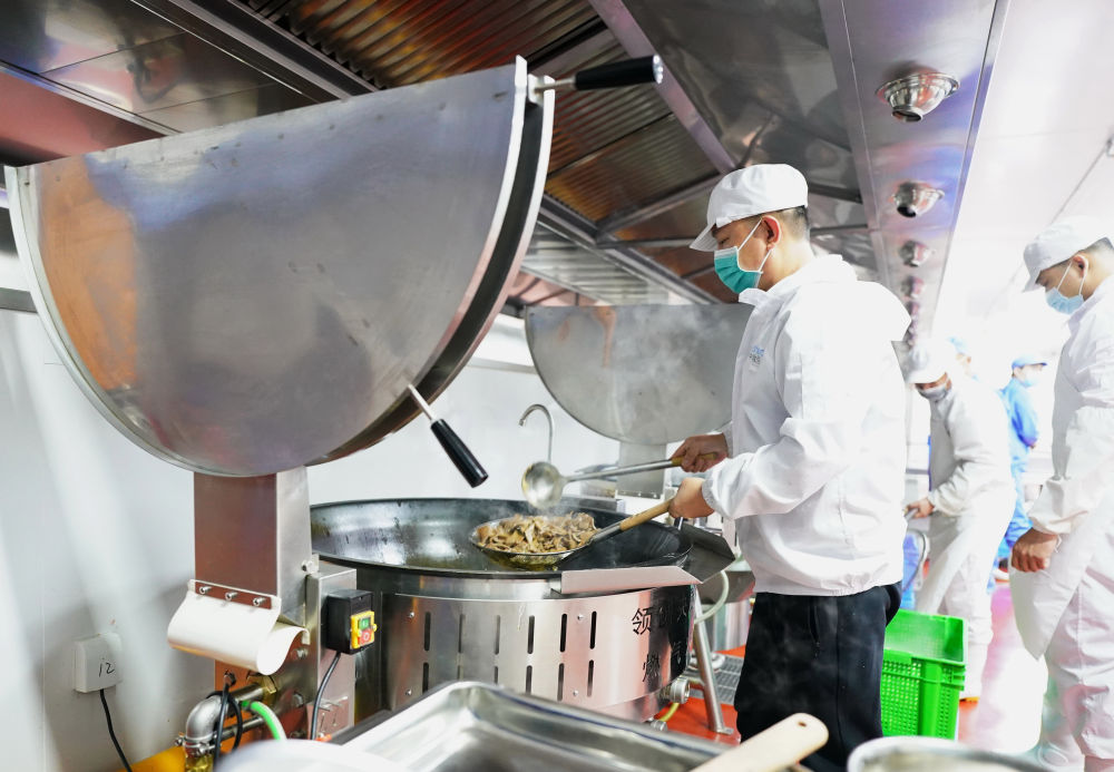 4月28日,唐山市路北区中央大厨房的工人在烹饪车间工作.